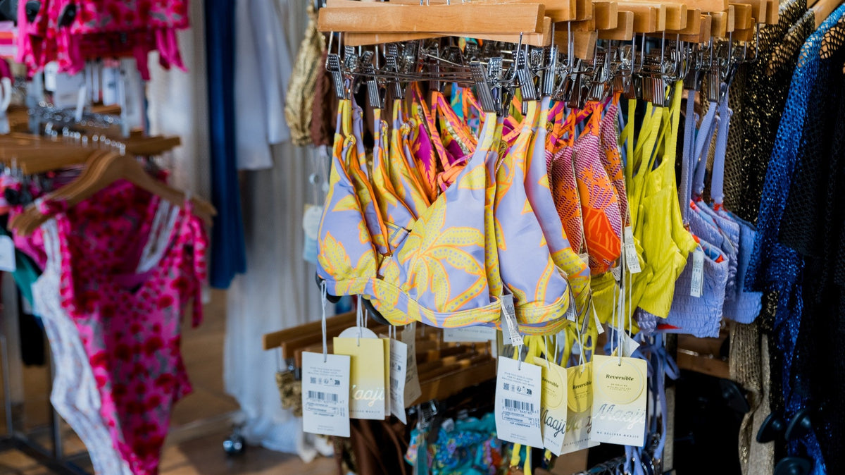 Rack of colorful bikini and swim tops in yellow, coral and pink prints at Swim City Downtown Sarasota