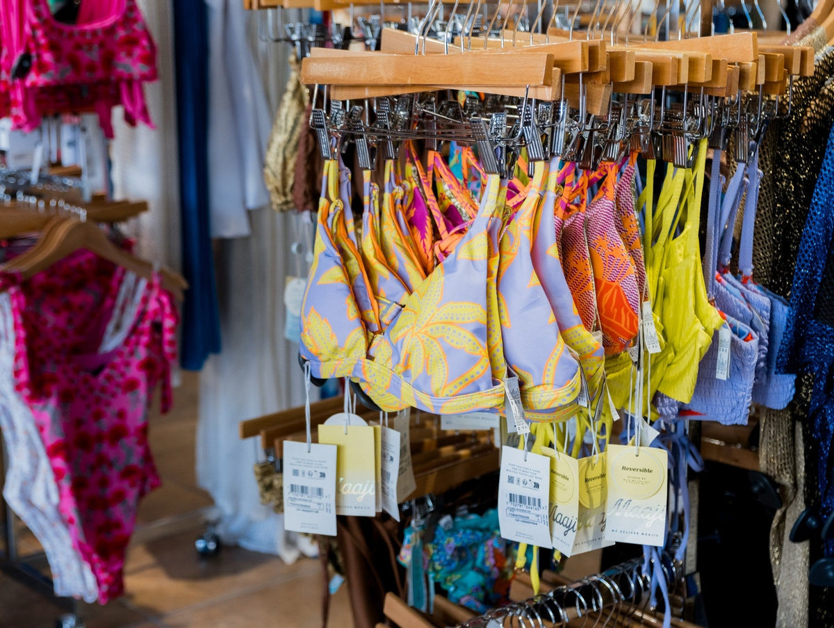 Rack of colorful bikini and swim tops in yellow, coral and pink prints at Swim City Downtown Sarasota