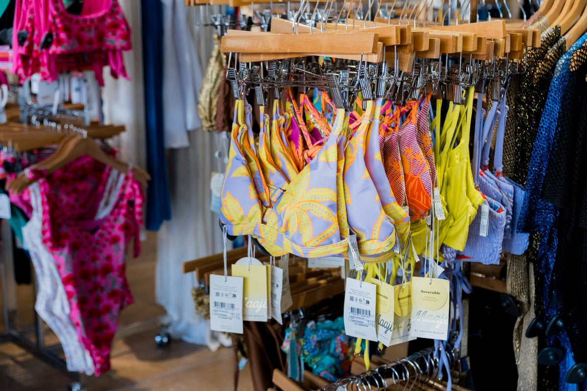 Rack of colorful bikini and swim tops in yellow, coral and pink prints at Swim City Downtown Sarasota